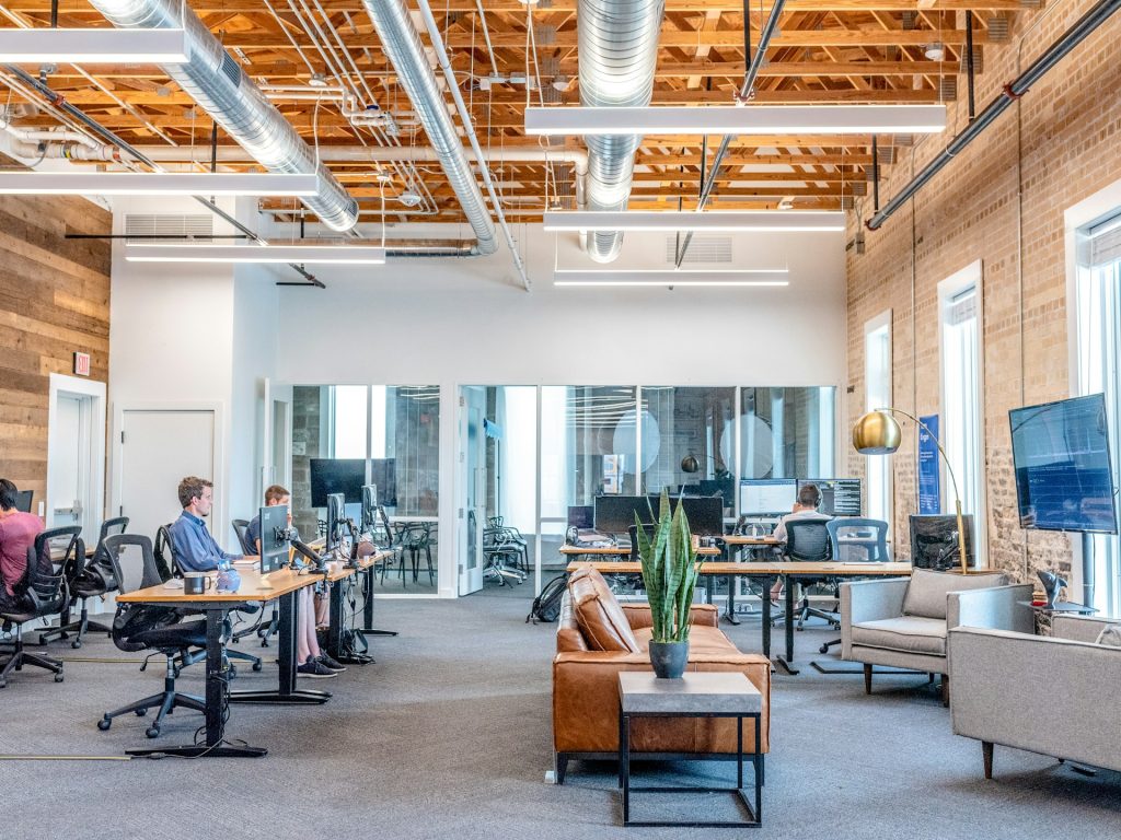 Espace de travail ouvert où des personnes font concilier ergonomie et travail sur écran grâce à des bonnes pratiques et du mobilier adapté